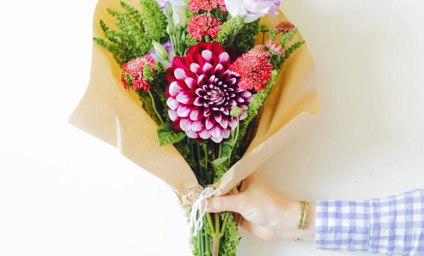 A hand-tied bunch of dahlias and amaranth in kraft paper.