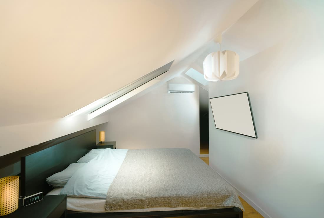 A white room under the rafters, lit by a skylight in the sloping ceiling.