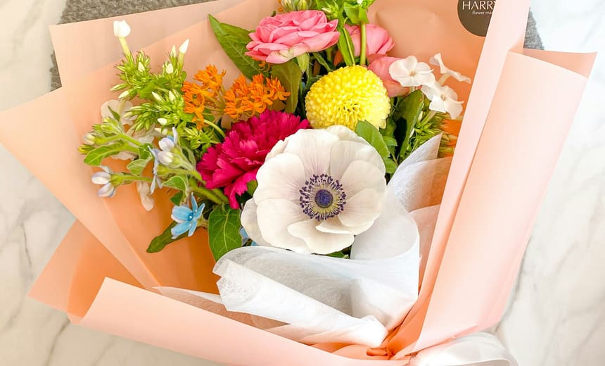 Un mix di stagione luminoso di anemoni, ranuncoli e dalie pompon in carta pesca.