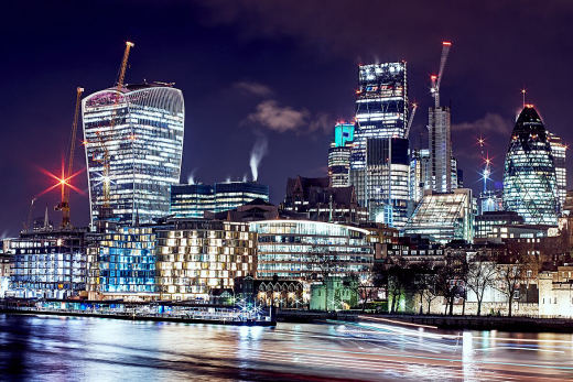 The City of London skyline lit at night, with the Walkie-Talkie and the Gherkin.