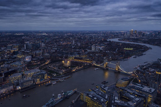 London at dusk from high up, the Thames winding away past Tower Bridge.