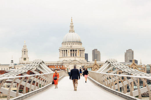 Looking north along the Millennium Bridge towards St Paul's Cathedral, with people walking across.