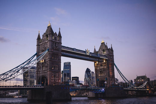Tower Bridge at dusk, lit against a violet sky, with the City behind it.